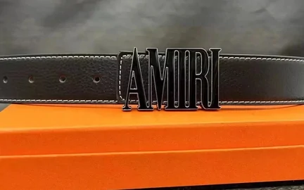 A brown leather belt coiled across an orange box, its metal buckle cut into block letters
