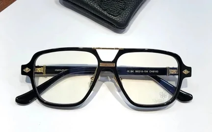 A pair of black double-bridge optical frames with clear lenses, photographed on a pale surface