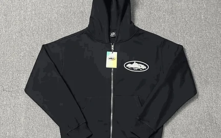 A navy zip-through hoodie on a dark background with a white card tag hanging from the sleeve