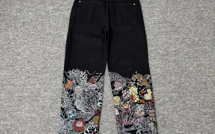 Black straight-leg jeans laid flat, with a dense floral print covering both lower legs