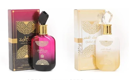 Two decorative fragrance bottles side by side, one in pink and one in gold, each in its own printed box