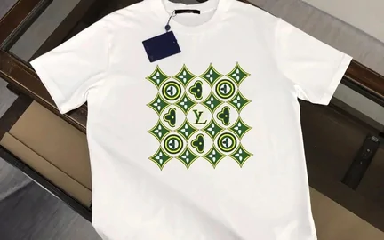 A white short-sleeved tee laid flat, printed with a small green geometric motif across the chest
